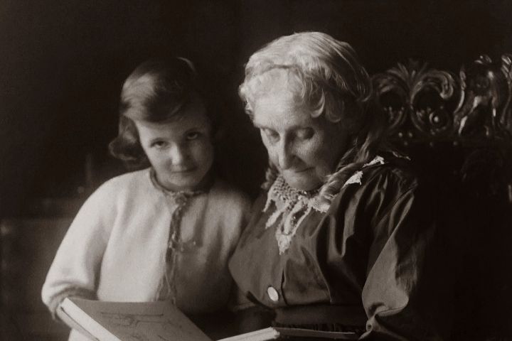 Old Woman Sitting on Chair And Reading A Book To A Child