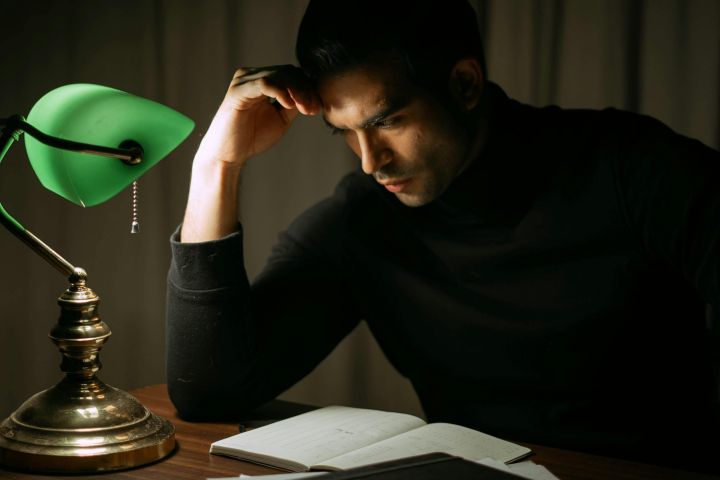 Serious man reading book in dark home office